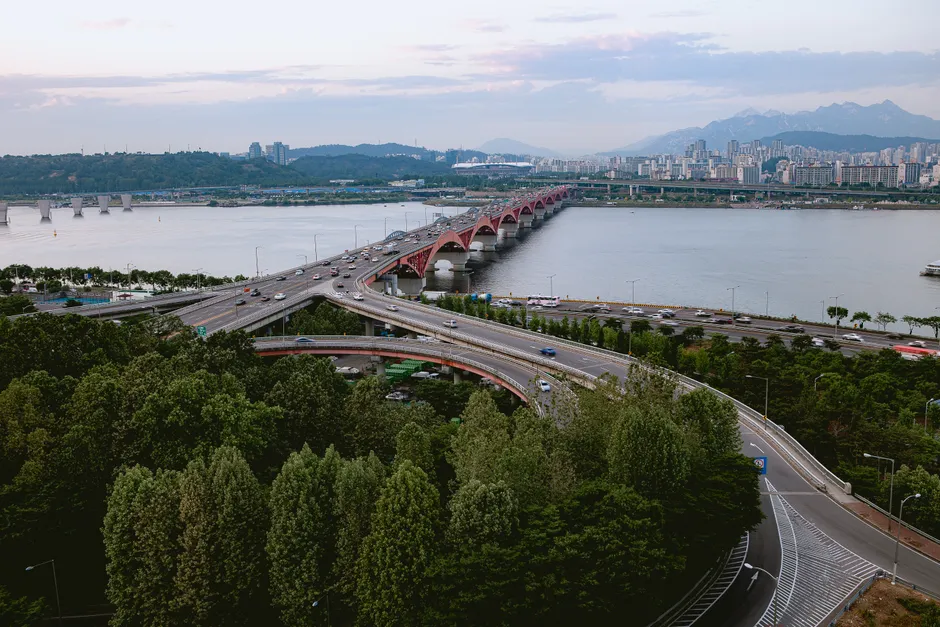 A stunning aerial view of a bridge over the Han River in Seoul with lush greenery and urban landscape.