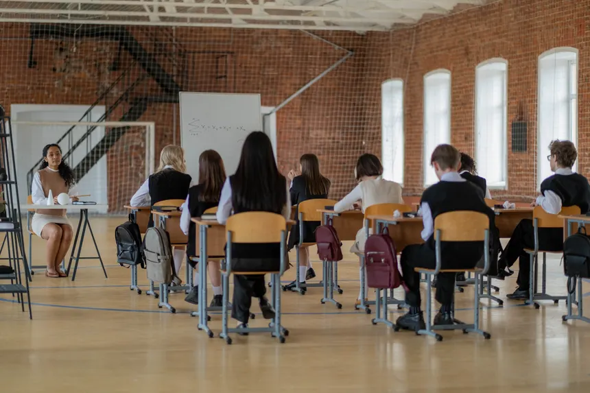 Students in a classroom setting facing a teacher, engaged in education.