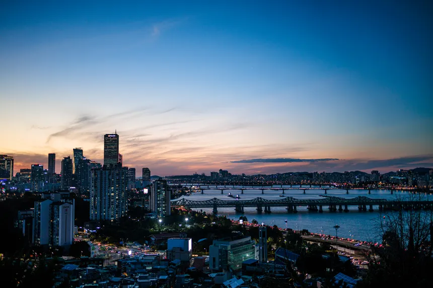 Explore the vibrant skyline of Seoul at twilight, featuring iconic buildings and the Han River.