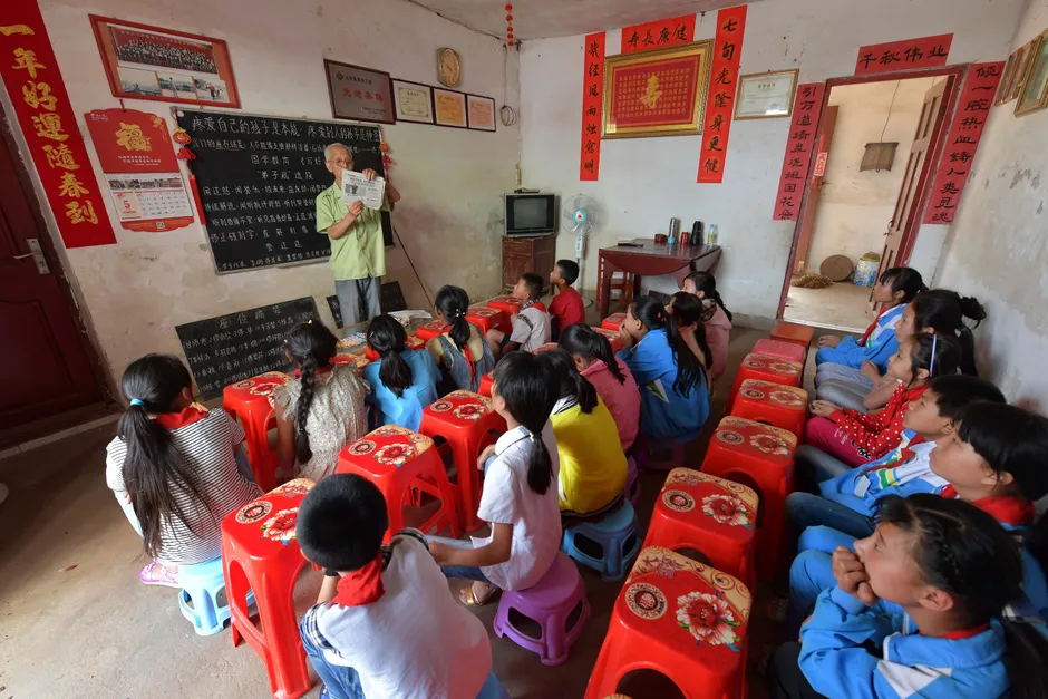 Children attentively listening to a teacher in a rural classroom setting in Jiangxi, China.