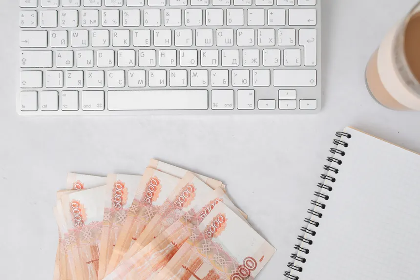 Russian banknotes with a keyboard and notebook on a white table surface, ideal for business finance themes.