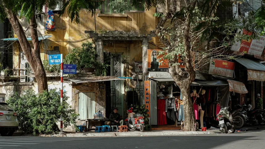 A lively street scene in Hanoi with shops, motorbikes, and pedestrians, capturing urban life.