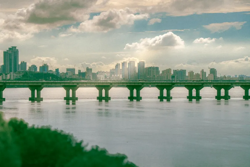 A stunning view of Seoul's skyline with a bridge spanning the Han River under a cloudy sky.