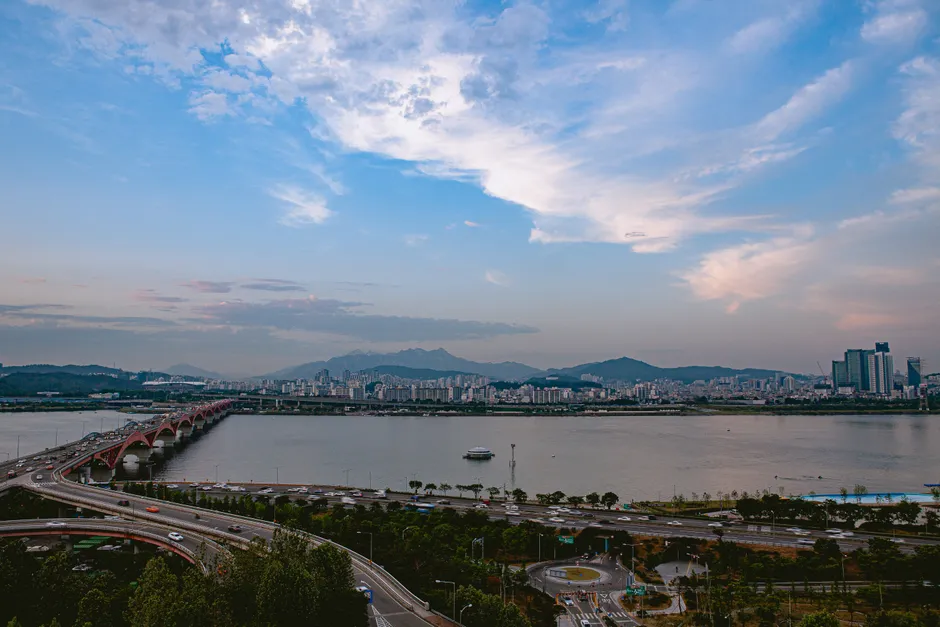 A captivating view of Seoul's skyline with the Han River and its iconic bridge under a beautiful sky.
