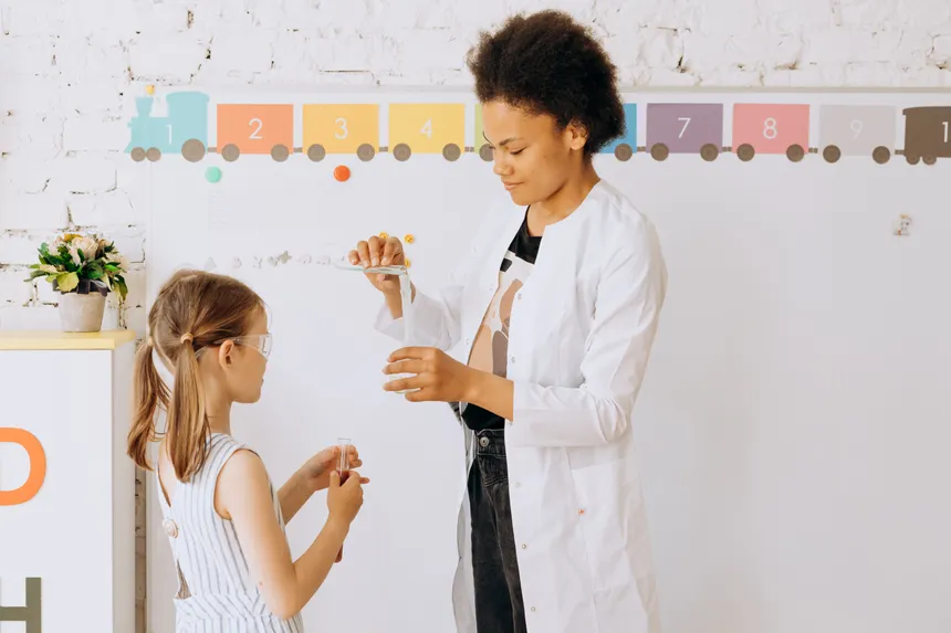 A teacher guides a child through a fun and educational science experiment in a classroom setting.